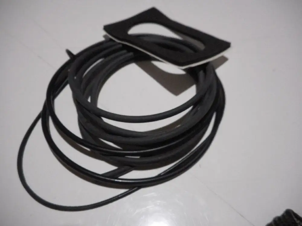 Schwarzes Gummiband und eine Dichtung auf einem weißen Untergrund, möglicherweise Teil eines Heizsystems von Remeha.